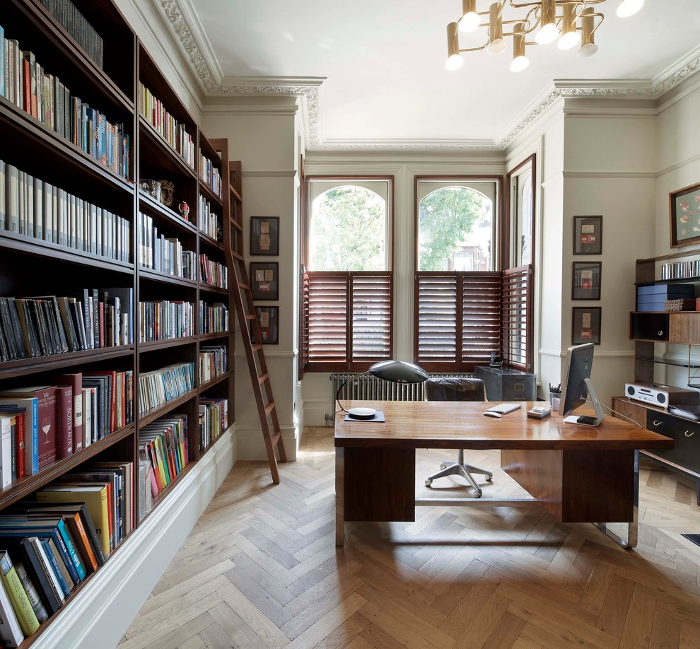 This is an example of a transitional home office in London with white walls, medium hardwood floors, a freestanding desk and beige floor.