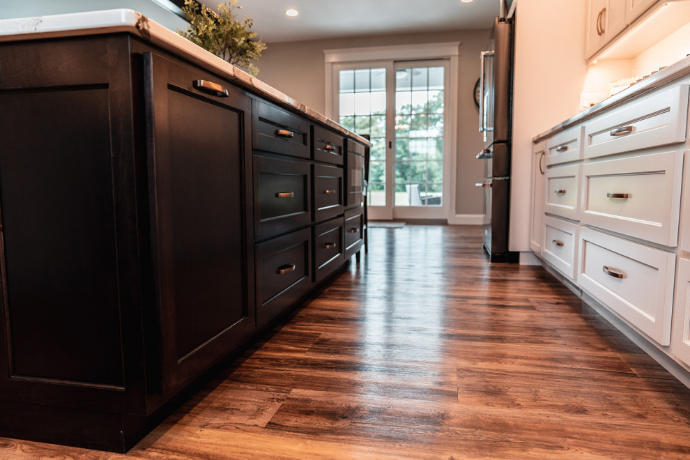 Inspiration for a large transitional l-shaped medium tone wood floor and brown floor open concept kitchen remodel with an undermount sink, flat-panel cabinets, white cabinets, quartz countertops, multicolored backsplash, quartz backsplash, black appliances, an island and multicolored countertops