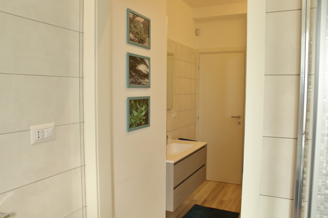 Idee per una stanza da bagno con doccia contemporanea di medie dimensioni con consolle stile comò, ante in legno scuro, doccia a filo pavimento, WC a due pezzi, piastrelle bianche, piastrelle in gres porcellanato, pareti bianche, pavimento in gres porcellanato, lavabo integrato, top in superficie solida e porta doccia scorrevole