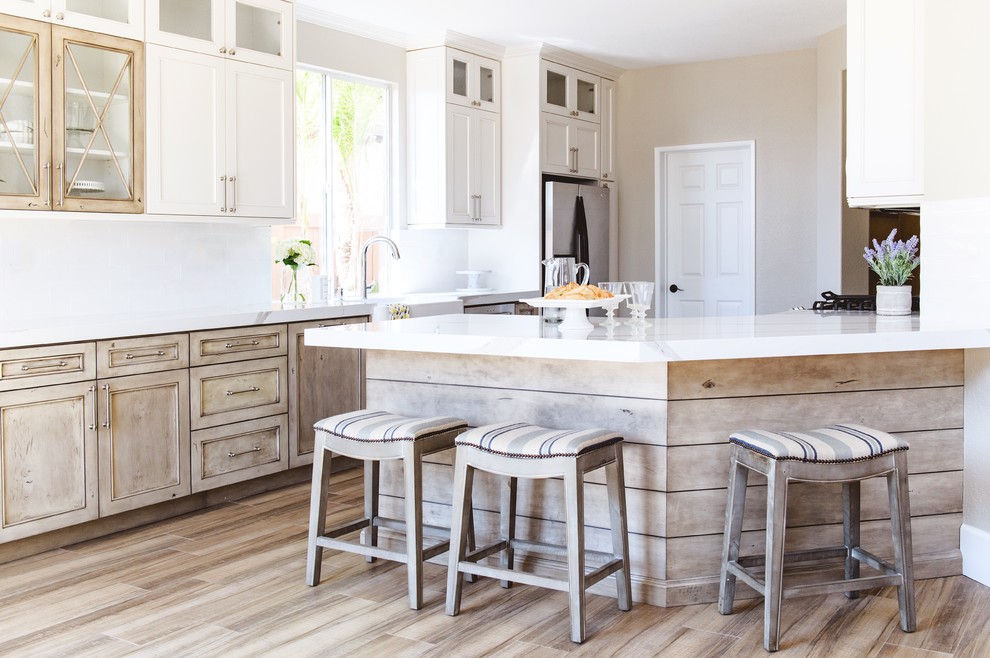 Mid-sized transitional galley medium tone wood floor and brown floor open concept kitchen photo in San Diego with a farmhouse sink, white backsplash, stainless steel appliances, a peninsula, shaker cabinets, white cabinets and quartzite countertops