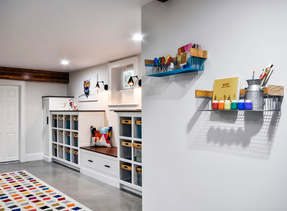 Photo of a large transitional gender-neutral kids' playroom for kids 4-10 years old in Newark with white walls, concrete floors and grey floor.