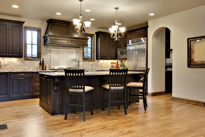 Design ideas for a mid-sized traditional galley eat-in kitchen in Atlanta with raised-panel cabinets, dark wood cabinets, granite benchtops, beige splashback, stone tile splashback, stainless steel appliances, light hardwood floors, with island and beige floor.