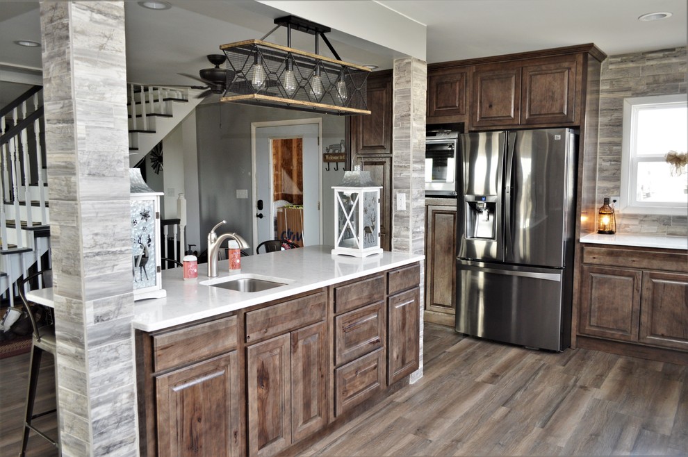 Large country u-shaped open plan kitchen in Chicago with a farmhouse sink, raised-panel cabinets, brown cabinets, quartzite benchtops, brown splashback, stainless steel appliances, with island, brown floor and white benchtop.