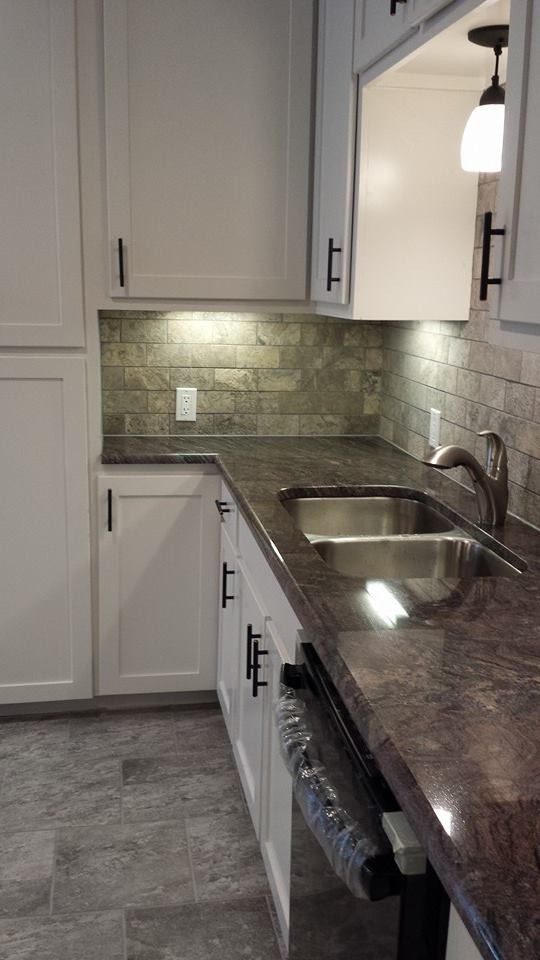 This is an example of a mid-sized traditional galley separate kitchen in Dallas with white cabinets, granite benchtops, white splashback, light hardwood floors, an undermount sink, shaker cabinets, stone tile splashback, black appliances and no island.