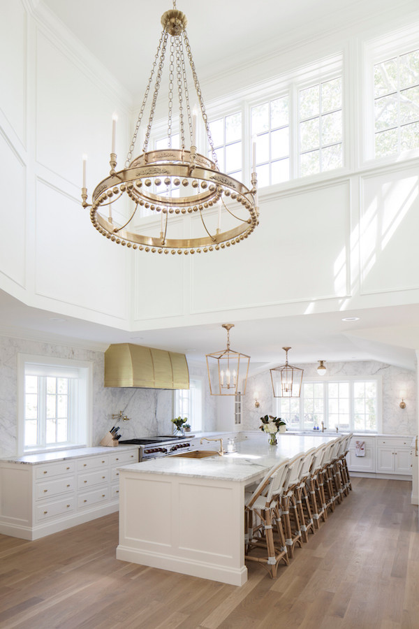 Open concept kitchen - huge traditional u-shaped light wood floor and brown floor open concept kitchen idea in Salt Lake City with a farmhouse sink, beaded inset cabinets, white cabinets, marble countertops, white backsplash, marble backsplash, stainless steel appliances and an island