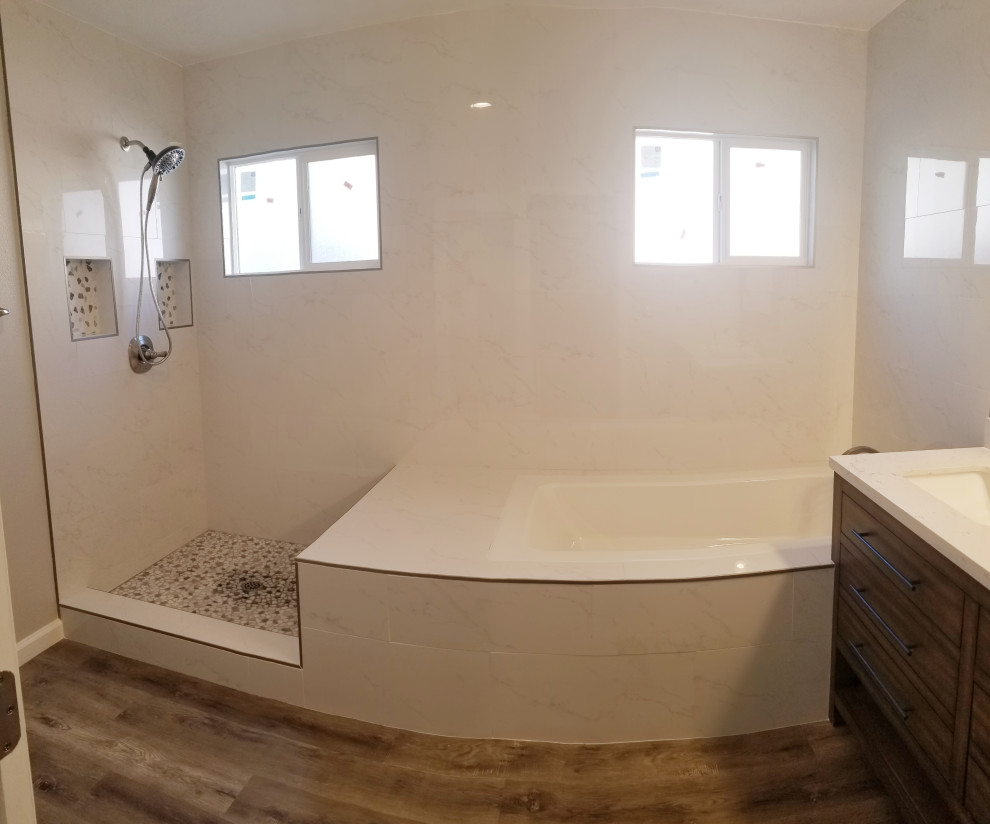На фото: главная ванная комната среднего размера в современном стиле с плоскими фасадами, коричневыми фасадами, японской ванной, угловым душем, раздельным унитазом, белой плиткой, керамогранитной плиткой, серыми стенами, полом из винила, врезной раковиной, столешницей из кварцита, серым полом, душем с распашными дверями, белой столешницей, тумбой под две раковины и напольной тумбой с