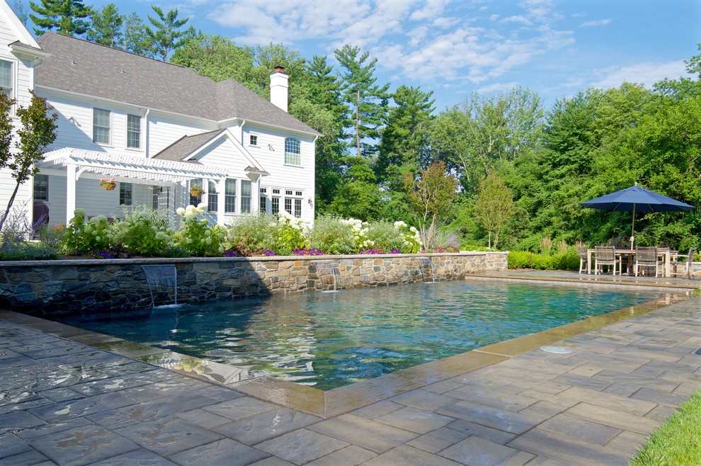 Photo of a large traditional backyard rectangular lap pool in Philadelphia with a water feature and concrete pavers.