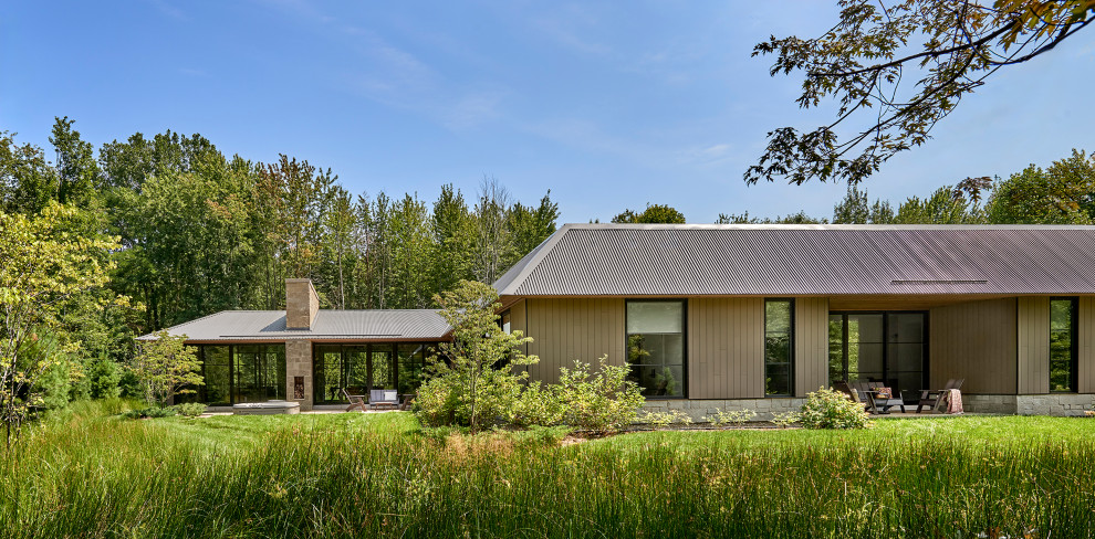 Large cottage beige one-story wood house exterior idea in Other with a hip roof, a metal roof and a gray roof