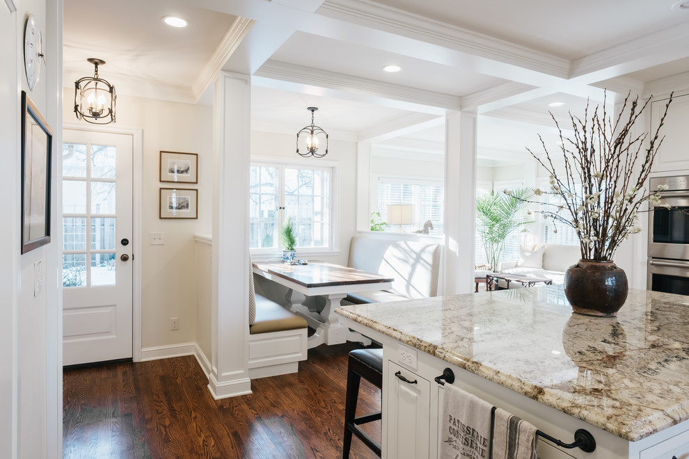 Design ideas for a mid-sized traditional l-shaped eat-in kitchen in Minneapolis with raised-panel cabinets, white cabinets, onyx benchtops, panelled appliances, light hardwood floors, with island and a farmhouse sink.