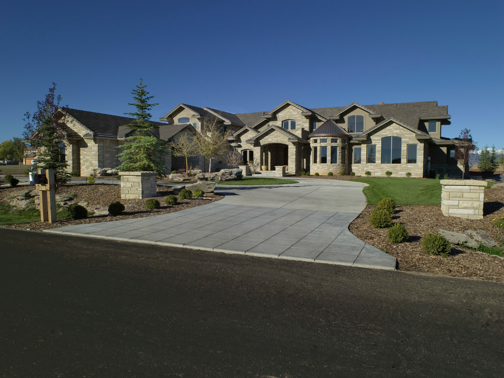 This is an example of a large traditional two-storey beige exterior in Denver with stone veneer and a hip roof.