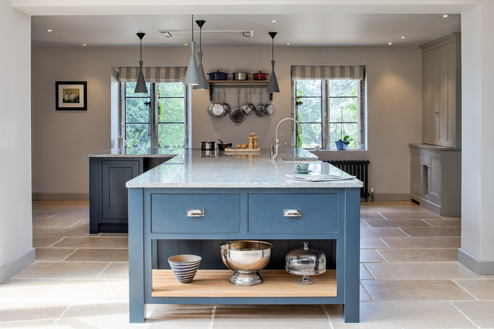 Inspiration for a large traditional eat-in kitchen in Wiltshire with a farmhouse sink, blue cabinets, with island, beige floor, grey benchtop, panelled appliances, limestone floors, shaker cabinets and granite benchtops.