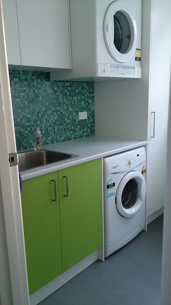 Inspiration for a large modern single-wall utility room in Melbourne with a drop-in sink, flat-panel cabinets, green cabinets, white walls, porcelain floors and laminate benchtops.