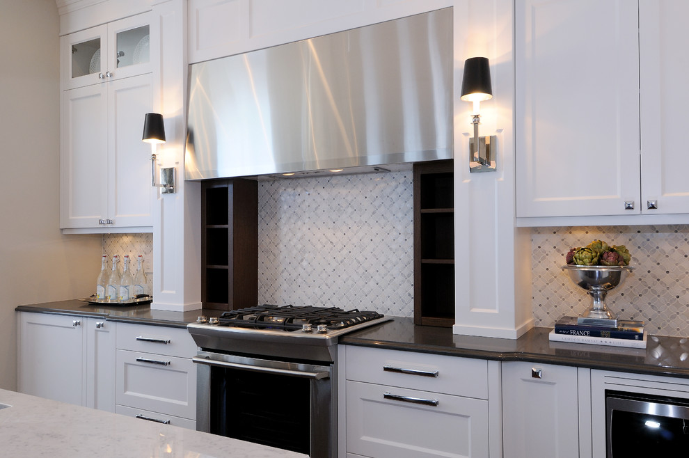 Example of a mid-sized transitional l-shaped dark wood floor eat-in kitchen design in Calgary with an undermount sink, recessed-panel cabinets, white cabinets, quartz countertops, multicolored backsplash, mosaic tile backsplash, stainless steel appliances and an island