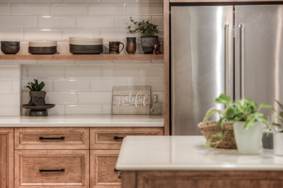 Kitchen - transitional l-shaped kitchen idea in Toronto with an undermount sink, shaker cabinets, light wood cabinets, white backsplash, stainless steel appliances, an island and white countertops