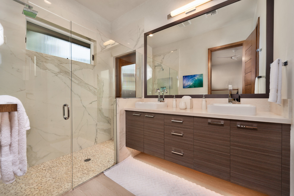 Mid-sized modern master bathroom in Hawaii with porcelain floors, flat-panel cabinets, brown cabinets, an alcove shower, white tile, marble, white walls, a vessel sink, limestone benchtops, a hinged shower door and beige floor.