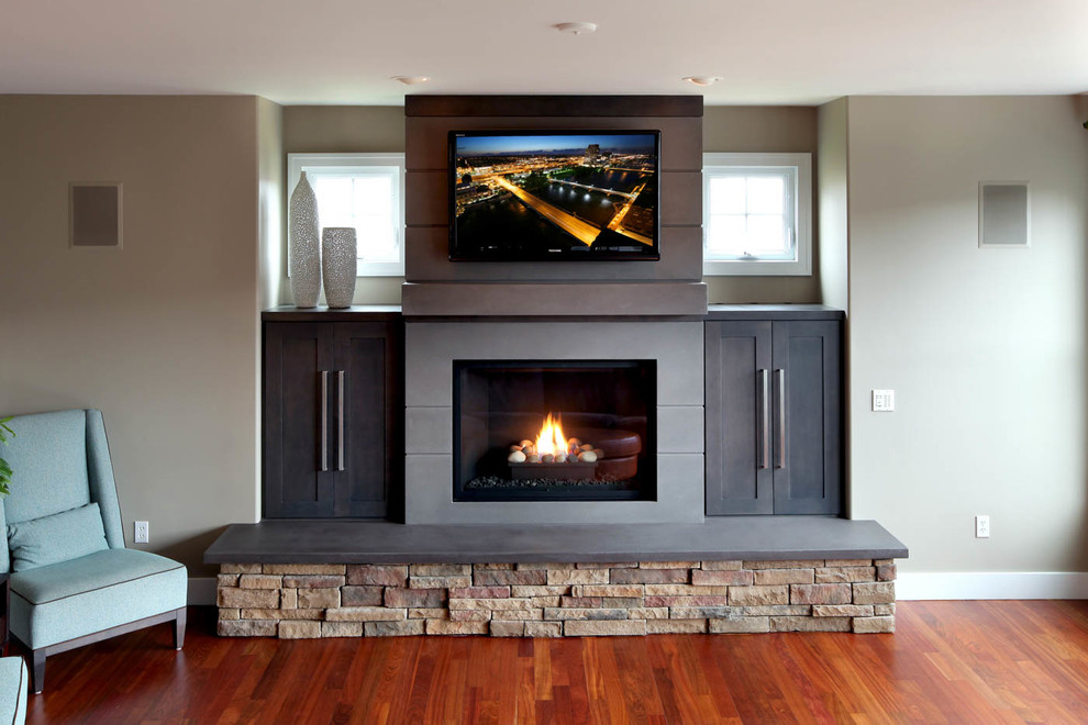 Photo of a transitional family room in Grand Rapids with a concrete fireplace surround.