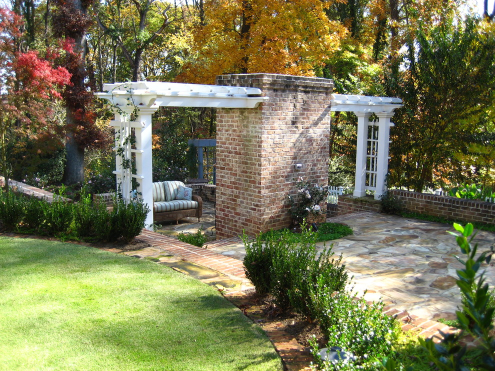 Inspiration for a traditional backyard patio in Other with natural stone pavers and a pergola.