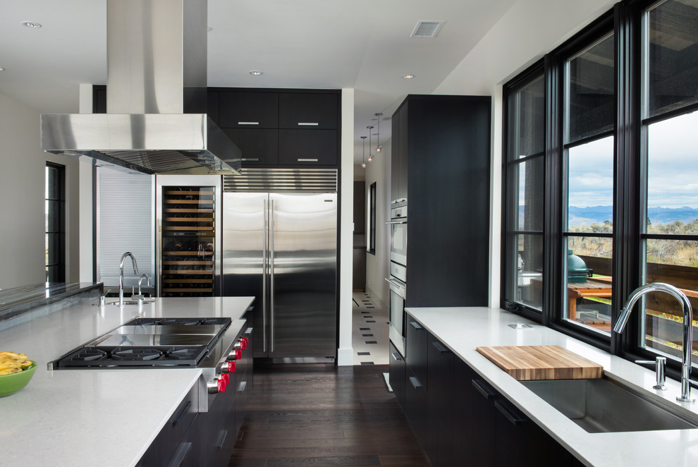 This is an example of a large contemporary l-shaped eat-in kitchen in Denver with an undermount sink, flat-panel cabinets, black cabinets, marble benchtops, stainless steel appliances, dark hardwood floors and with island.