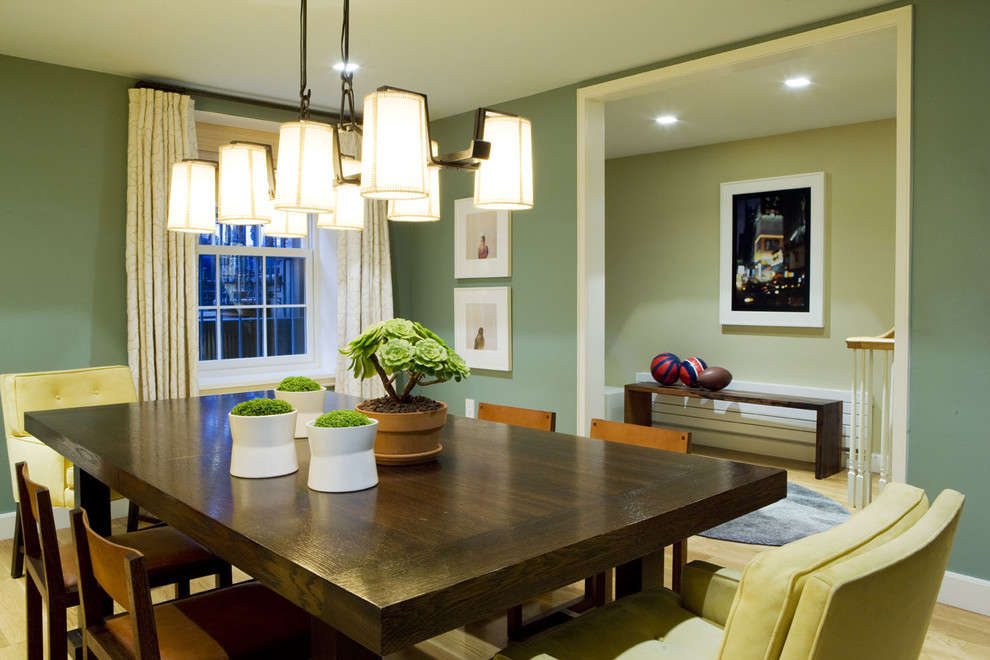 Contemporary dining room in New York with green walls and light hardwood floors.