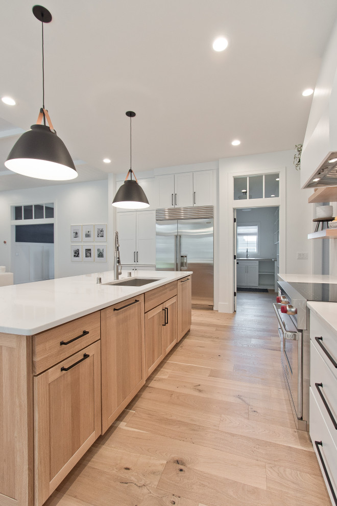 Inspiration for a large transitional light wood floor and brown floor kitchen pantry remodel with an undermount sink, flat-panel cabinets, light wood cabinets, quartz countertops, an island and white countertops
