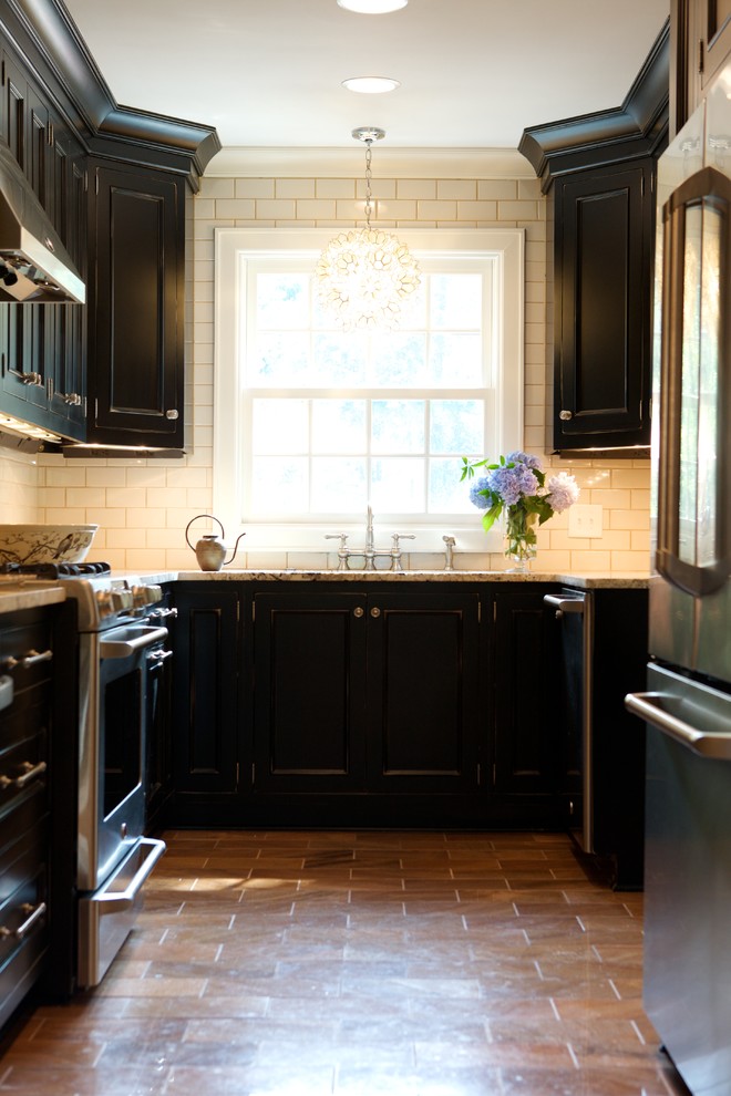 Inspiration for a traditional u-shaped separate kitchen in Raleigh with stainless steel appliances, recessed-panel cabinets, black cabinets, white splashback and subway tile splashback.