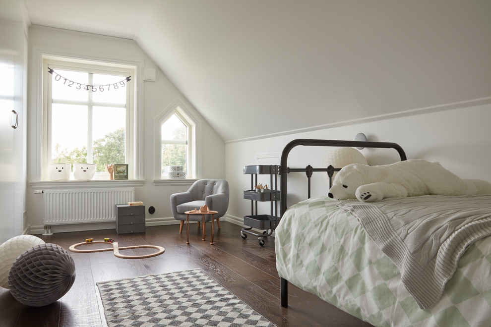 This is an example of a mid-sized traditional gender-neutral kids' room for kids 4-10 years old in Stockholm with white walls and dark hardwood floors.