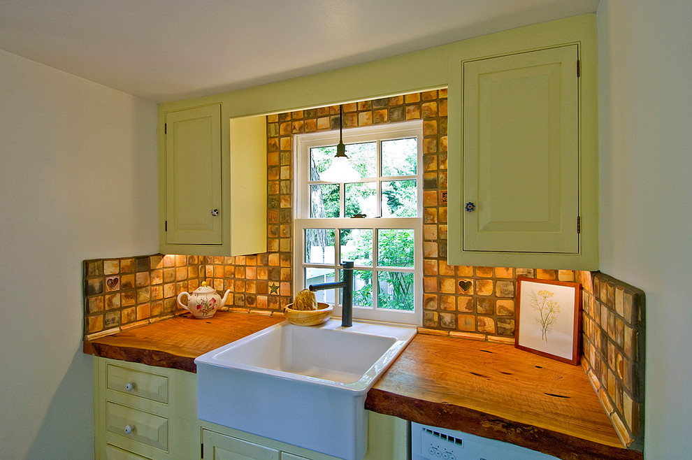Photo of a small country u-shaped separate kitchen in Philadelphia with a farmhouse sink, raised-panel cabinets, yellow cabinets, terra-cotta splashback, white appliances, slate floors, no island, wood benchtops and beige splashback.