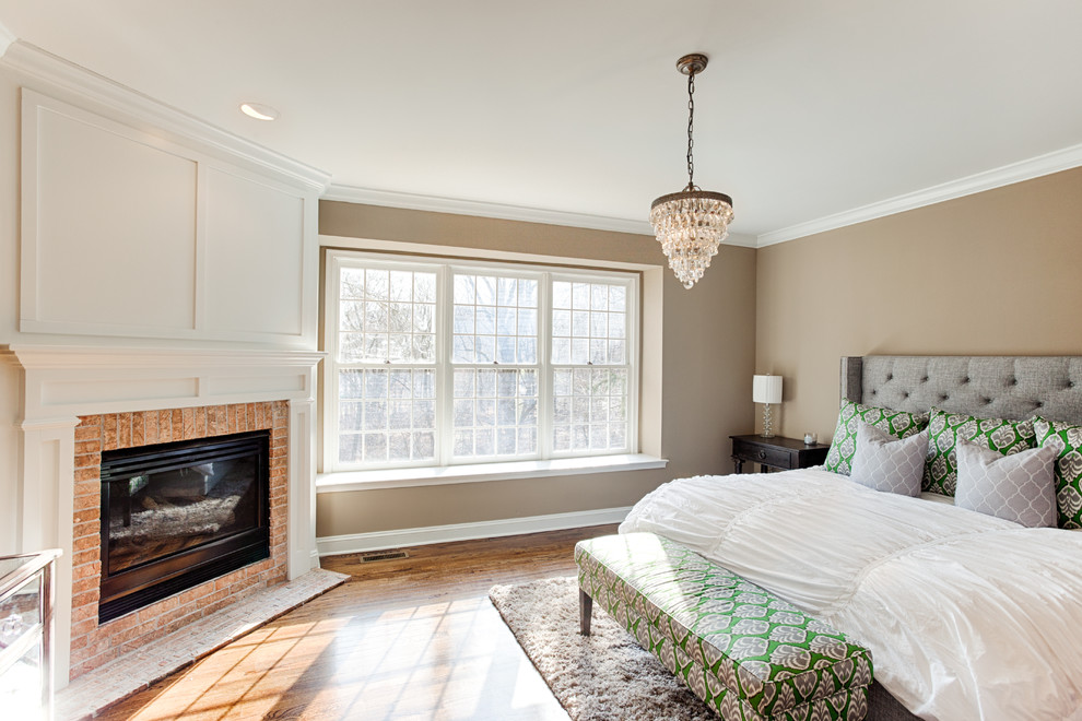 Inspiration for a mid-sized transitional master bedroom in Philadelphia with beige walls, medium hardwood floors, a corner fireplace, a brick fireplace surround and brown floor.