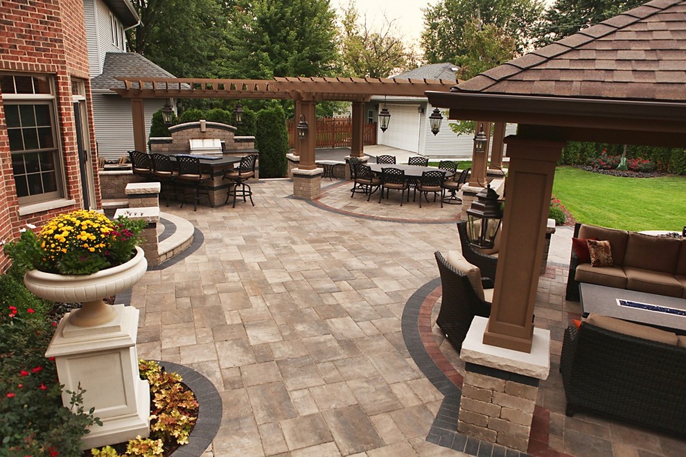 Photo of a traditional backyard patio in Chicago with an outdoor kitchen, brick pavers and a pergola.