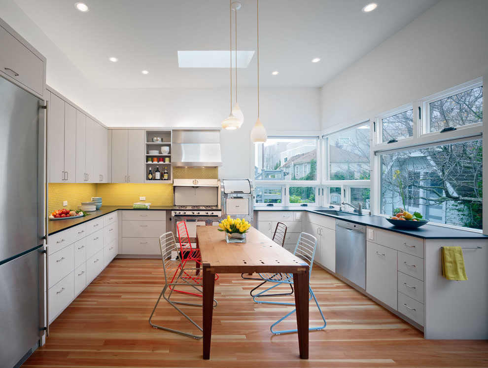 This is an example of a large contemporary u-shaped eat-in kitchen in San Francisco with stainless steel appliances, grey cabinets, an undermount sink, flat-panel cabinets, yellow splashback, mosaic tile splashback and no island.