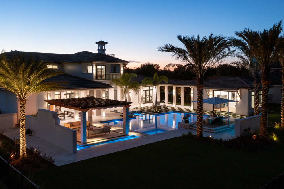 This is an example of an expansive mediterranean backyard custom-shaped infinity pool in Tampa with with a pool and tile.