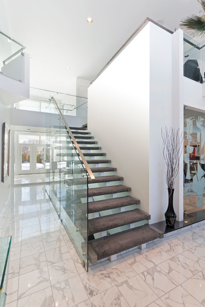 Mid-sized modern carpeted floating staircase in Other with open risers and glass railing.