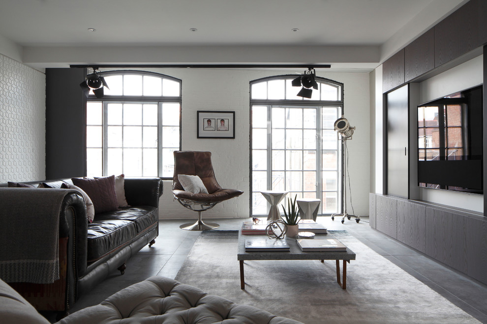 Photo of a mid-sized industrial formal open concept living room in London with concrete floors, a wall-mounted tv and white walls.
