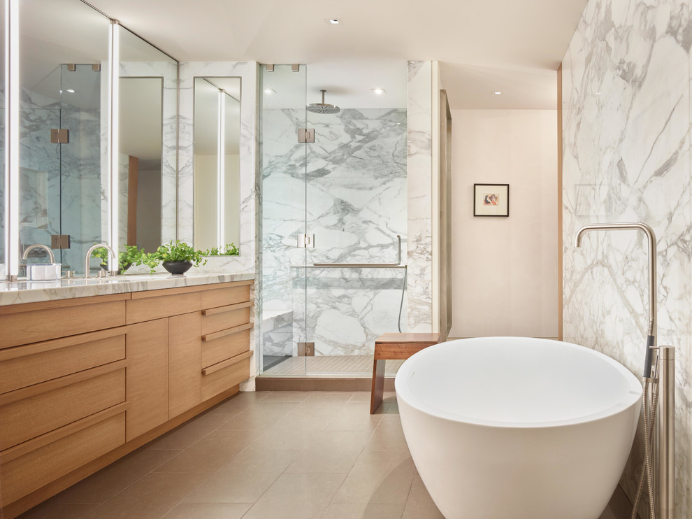 Design ideas for a contemporary master bathroom in Omaha with a freestanding tub, an alcove shower, stone tile, porcelain floors, marble benchtops, light wood cabinets, multi-coloured tile and a hinged shower door.