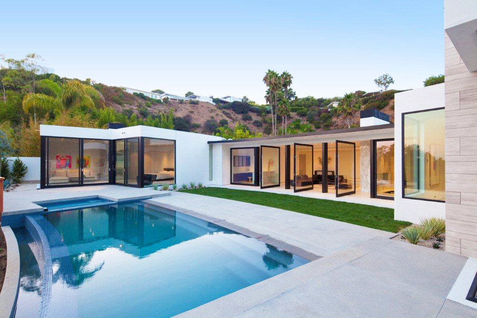 Inspiration for a mid-sized modern backyard rectangular infinity pool in Los Angeles with concrete slab.