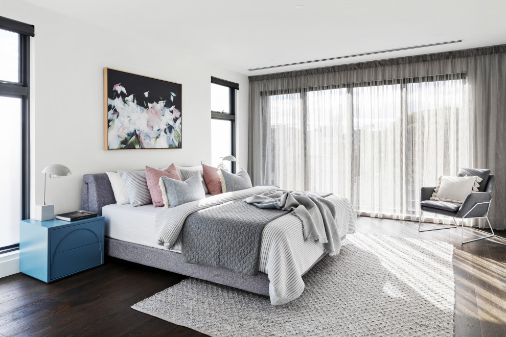This is an example of a large modern master bedroom in Melbourne with white walls, dark hardwood floors and brown floor.