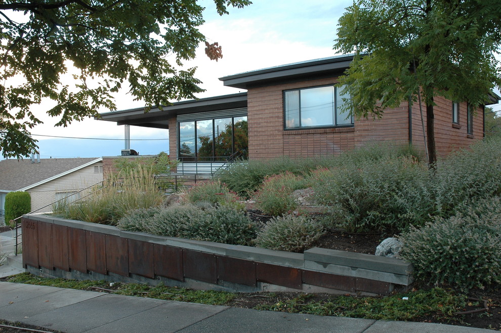 Design ideas for a mid-sized modern front yard partial sun xeriscape for summer in Salt Lake City with a retaining wall.