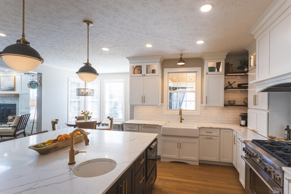 Eat-in kitchen - large transitional u-shaped medium tone wood floor and brown floor eat-in kitchen idea in Cincinnati with a farmhouse sink, shaker cabinets, white cabinets, granite countertops, white backsplash, subway tile backsplash, stainless steel appliances, an island and white countertops