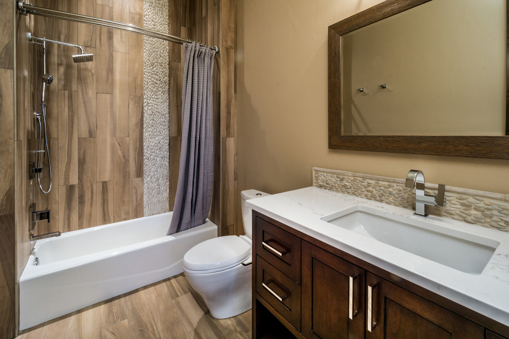 Design ideas for a mid-sized asian master bathroom in Other with beaded inset cabinets, dark wood cabinets, an alcove tub, a shower/bathtub combo, a two-piece toilet, stone tile, beige walls, ceramic floors, an undermount sink and marble benchtops.