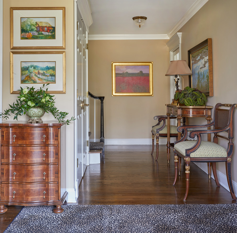 Traditional Rumson Home - An eclectic foyer welcomes visitors into this traditional home. A matching leopard area rug at the entry door and stair runner. An antique console and flanking re-upholstered side chairs lead you into the home with a poppy landscape framed artwork as the end of the hall vista.