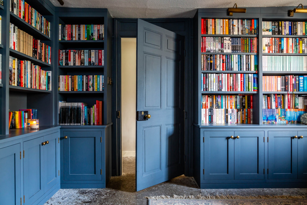 Foto de biblioteca en casa clásica de tamaño medio sin televisor con paredes azules, suelo de pizarra, estufa de leña, marco de chimenea de piedra y suelo gris