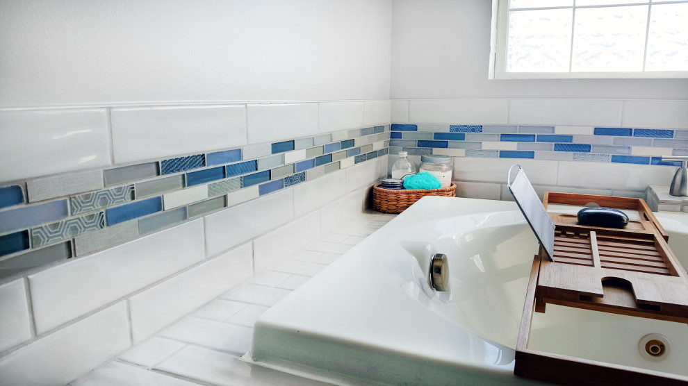 Inspiration for a mid-sized modern master bathroom in Other with blue cabinets, a drop-in tub, blue tile, glass tile, white walls, onyx benchtops, brown floor, beige benchtops, a single vanity and a built-in vanity.