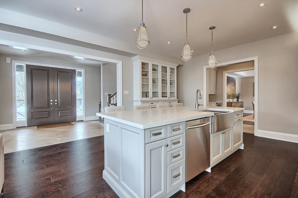 Design ideas for a mid-sized traditional single-wall open plan kitchen in Toronto with a farmhouse sink, beaded inset cabinets, white cabinets, quartz benchtops, white splashback, stainless steel appliances, dark hardwood floors, with island and porcelain splashback.
