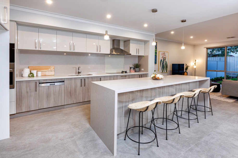 Photo of a contemporary galley open plan kitchen in Perth with a double-bowl sink, flat-panel cabinets, grey cabinets, quartz benchtops, grey splashback, stainless steel appliances, ceramic floors, grey floor and white benchtop.