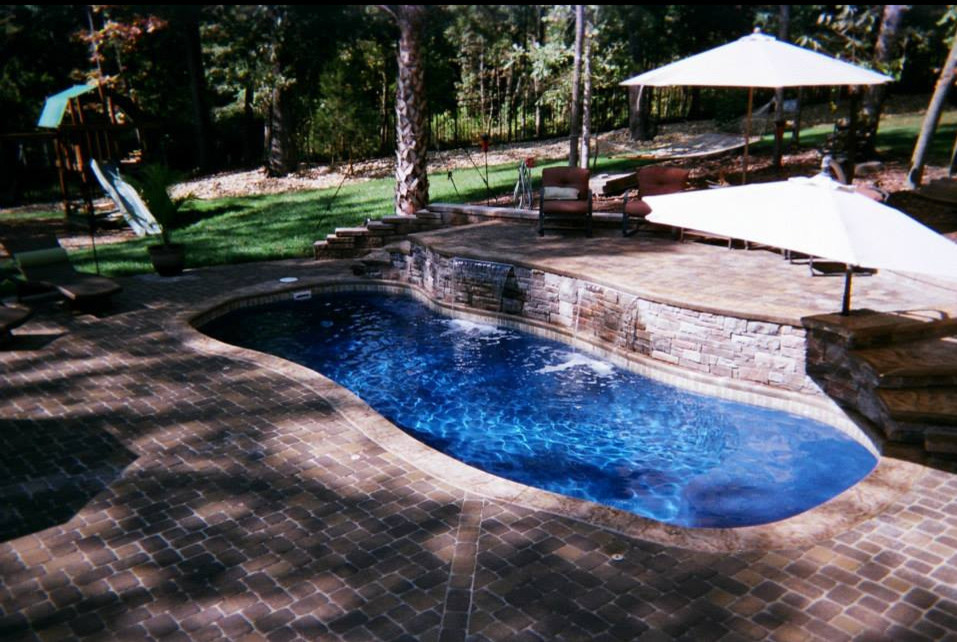 Inspiration for a backyard kidney-shaped natural pool in Charlotte with a water feature and natural stone pavers.
