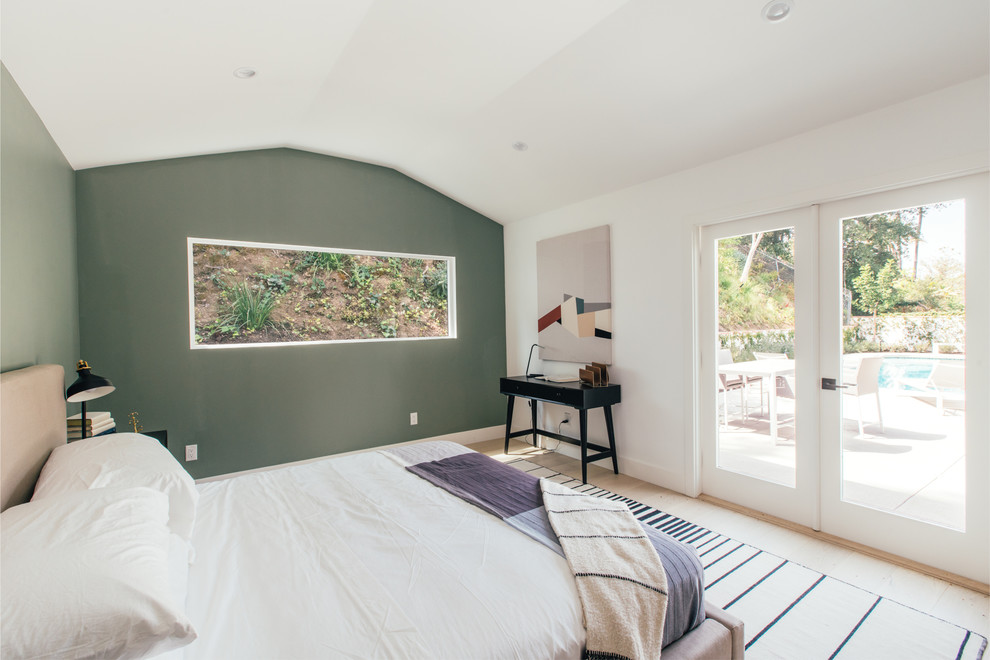 This is an example of a contemporary master bedroom in Los Angeles with green walls, light hardwood floors and beige floor.