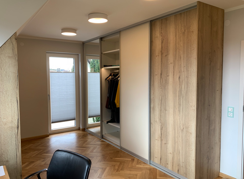 Photo of a large contemporary gender neutral dressing room in Nuremberg with light hardwood flooring and brown floors.