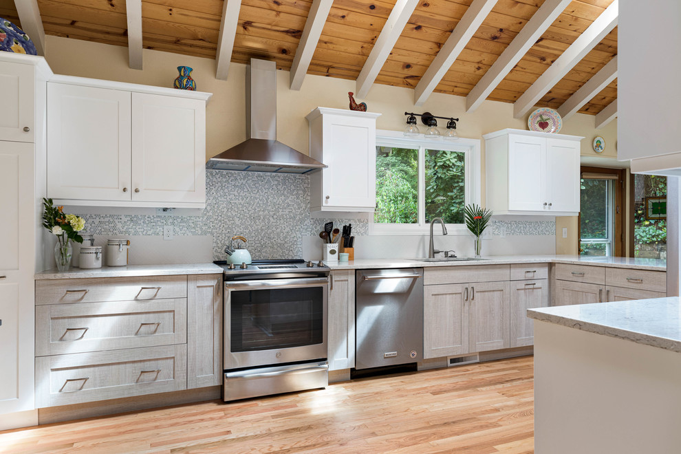 This is an example of a large country u-shaped eat-in kitchen in Seattle with an undermount sink, shaker cabinets, grey cabinets, quartz benchtops, multi-coloured splashback, mosaic tile splashback, stainless steel appliances, light hardwood floors, a peninsula, grey benchtop and beige floor.