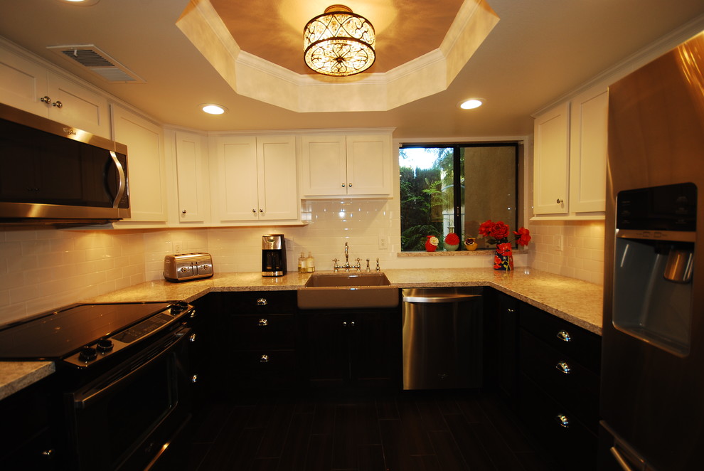 Small transitional u-shaped porcelain tile eat-in kitchen photo with a farmhouse sink, shaker cabinets, white cabinets, quartz countertops, white backsplash, subway tile backsplash, stainless steel appliances and gray walls