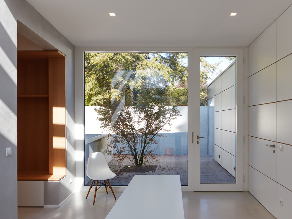 Photo of a mid-sized contemporary hallway in Other with white walls, grey floor and terrazzo floors.